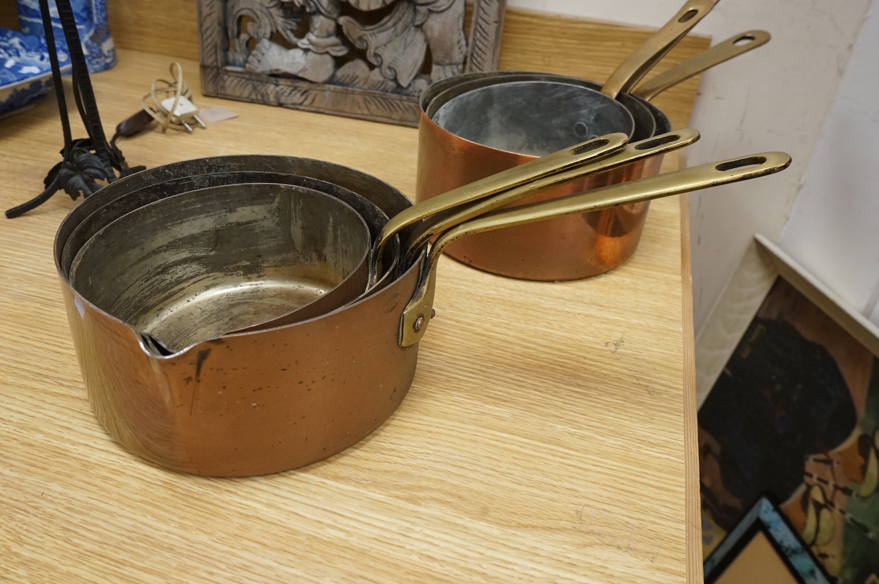 A set of three graduated copper and brass handled Saucepans and a similar set with pouring lid, largest 40cm in length